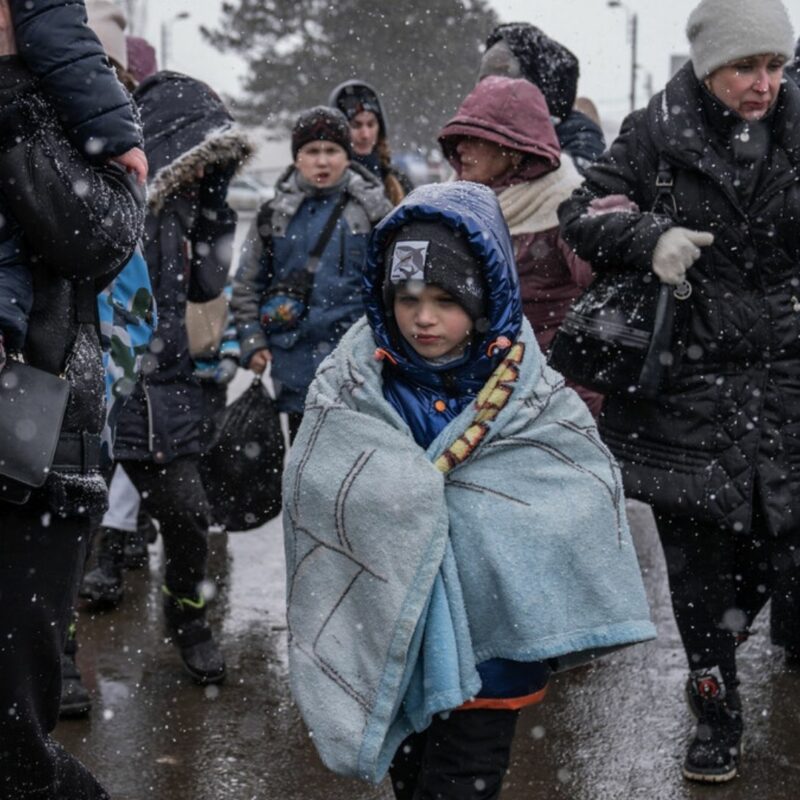 A child wrapped in blankets fighting his way through snowfall on the Ukraine-Romania border