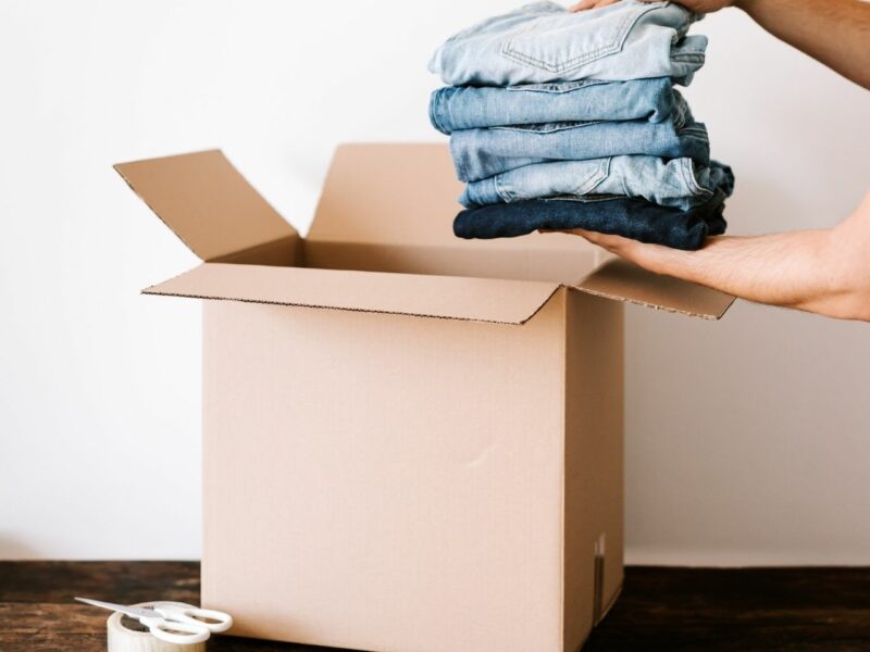 A pair of hands putting clothes into a cardboard box