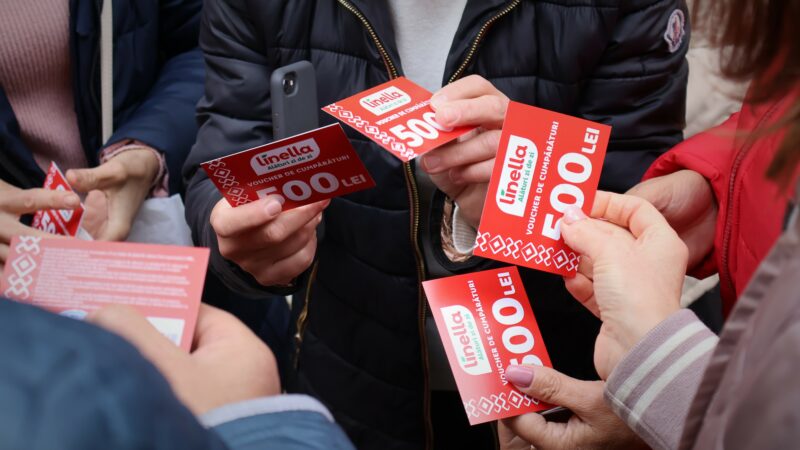 Female social workers hold red food vouchers for distribution to foster families in Moldova