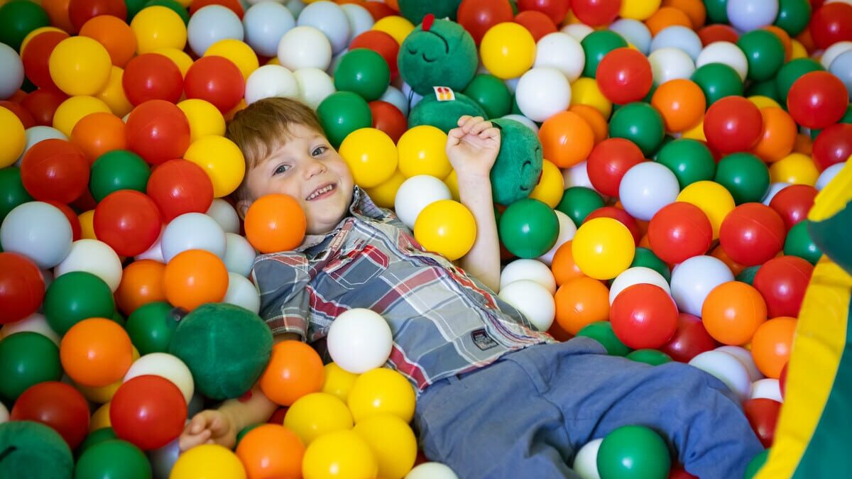 Nikita sits smiling in a colourful ball pit.