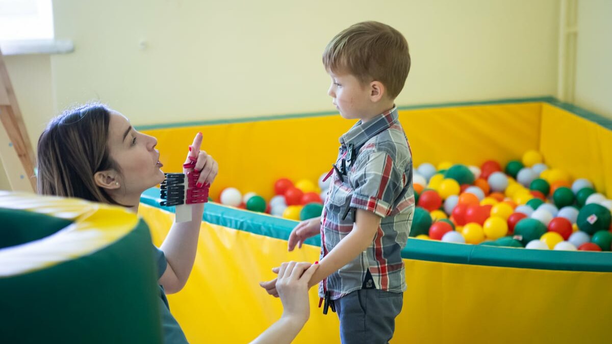 Nikita spends time together with a support worker, who is kneeling down to his level to talk to him.
