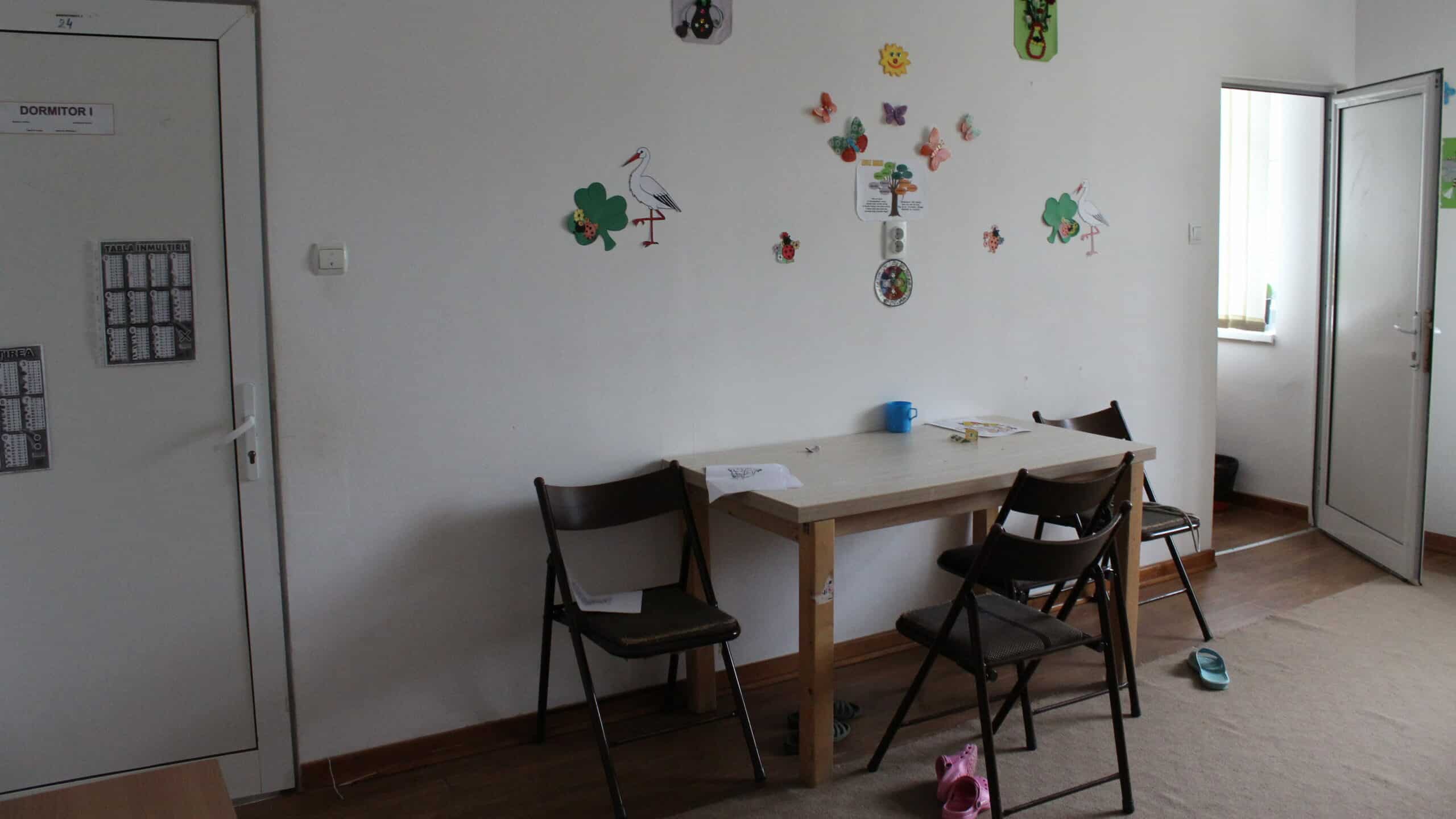 A desk with children's drawing on the wall at an orphanage in Romania.