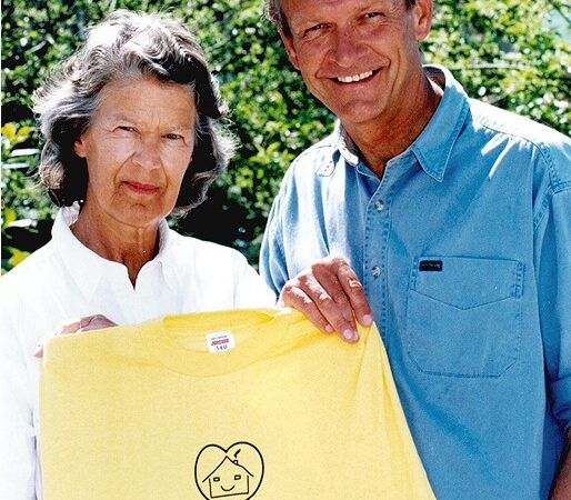 Mark and Caroline holding a yellow Hope and Homes for Children t-shirt