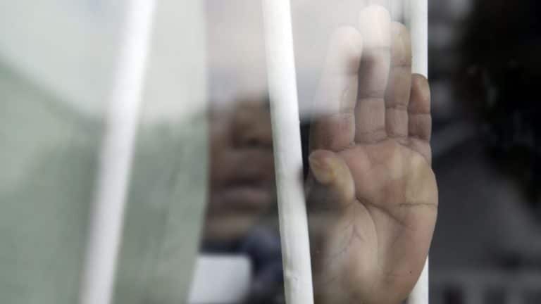 A young child's hand held pressed against a window