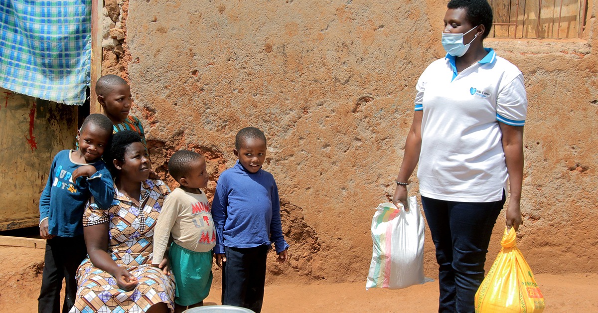 A Rwandan mother, Valerie, crouches, surrounded by her four children outside their home